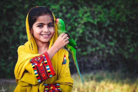 A girl poses for a photo with a parrot